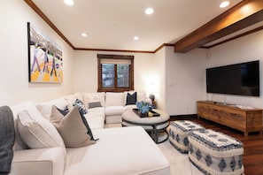 A modern living room with a sectional sofa, a round coffee table, and a flat-screen TV. - New! Riverside Townhome | Hot Tub | 3 Min to Beaver Creek (Avon)