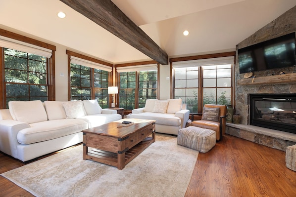 A spacious living room with a fireplace, large windows, and a cozy seating area. - New! Riverside Townhome | Hot Tub | 3 Min to Beaver Creek (Avon)