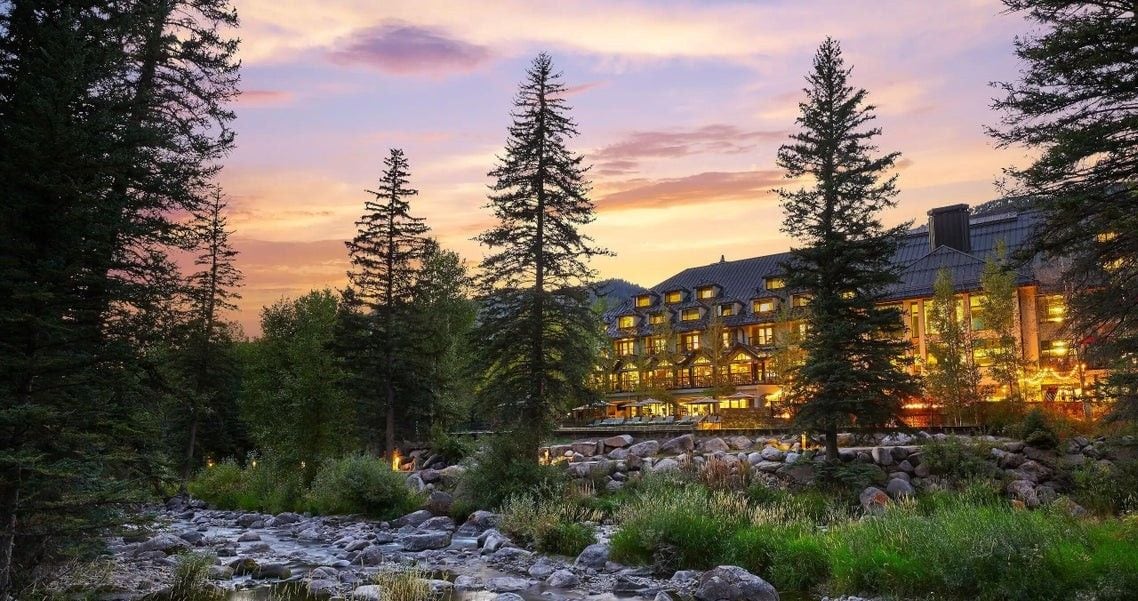 Un chalet doté de plusieurs pièces, entouré d’un paysage boisé et bordé par un ruisseau.