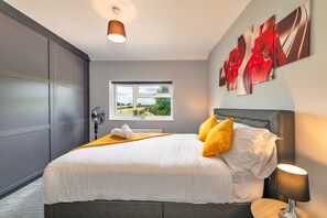 A modern bedroom with a large bed, a window with a view, and artwork on the wall. - Mill House, Staffordshire (Stafford)