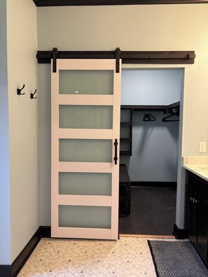 A room with a sliding door leading to a closet with hanging storage.