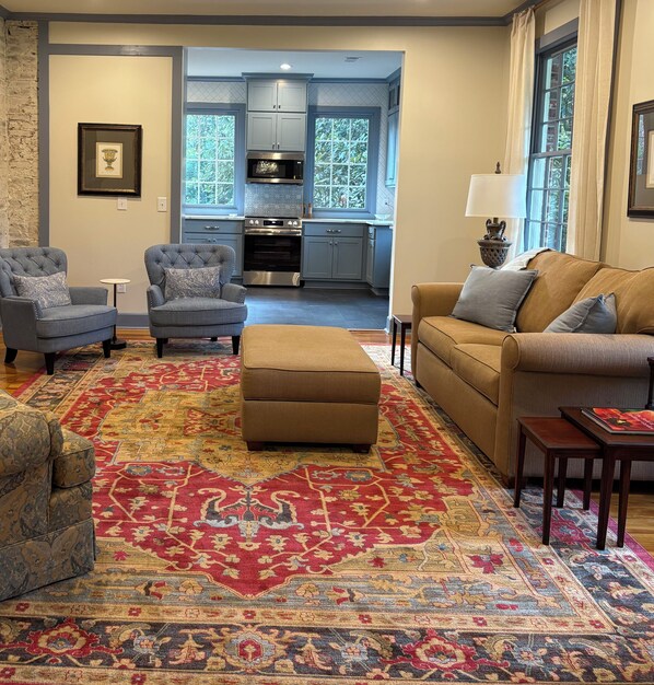 A living room with a patterned carpet, two armchairs, a sofa, and a coffee table.
