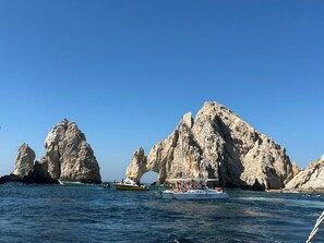A boat named Cabo Blue in a body of water with rocky cliffs in the background. - LUXURY TWO BEDROOM PRESIDENTIAL SUITE at Grand Solmar Land’s End Cabo San Lucas (Cabo San Lucas)