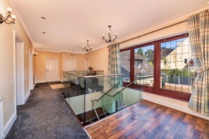 A spacious hallway with a glass staircase leading to a balcony with a view of the outside. - Tinacre (Wolverhampton)