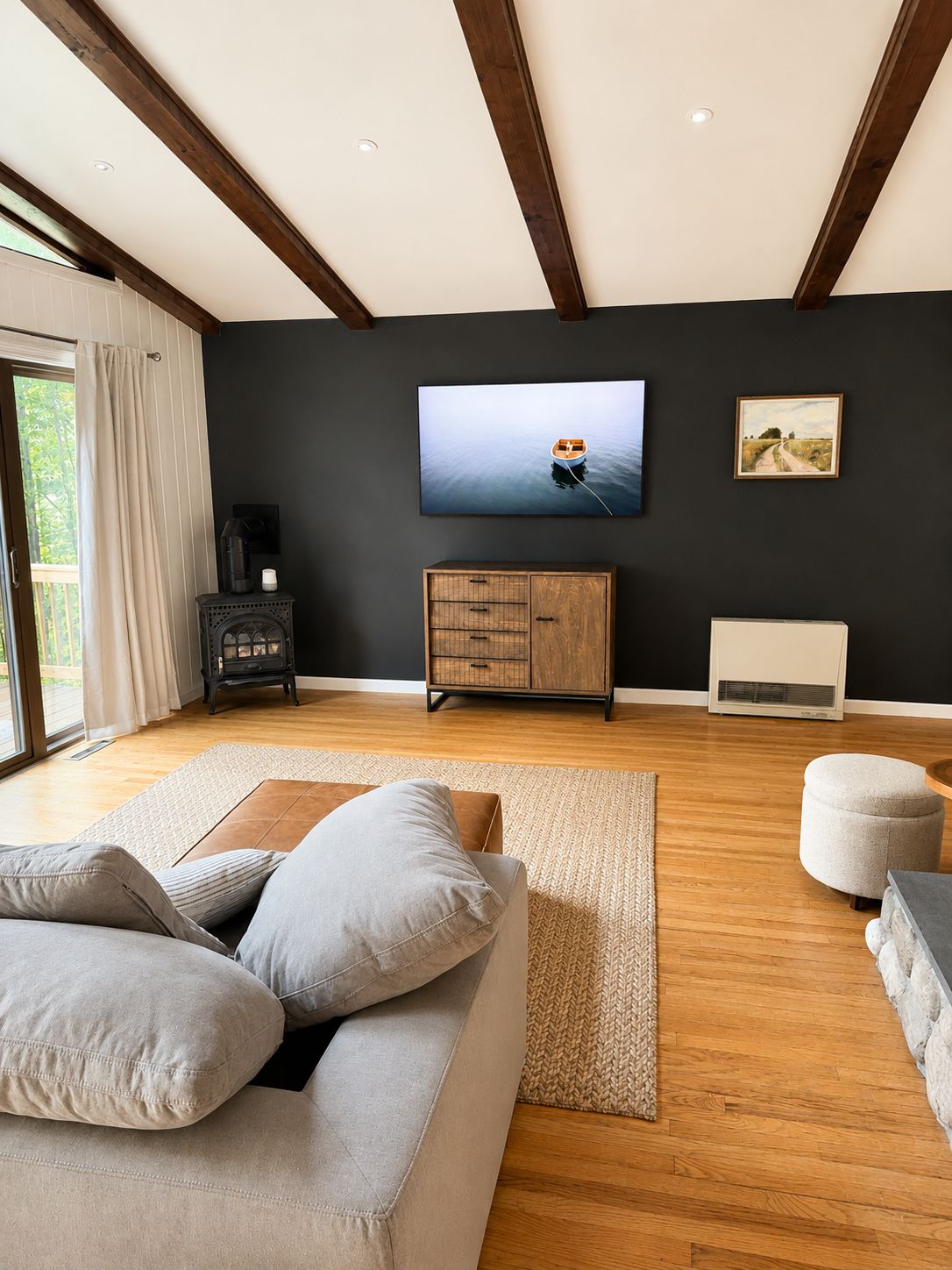 En moderne stue med sofa, skammel og et fladskærms-tv på væggen.