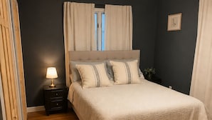 Una camera da letto con un letto, una lampada da comodino e una finestra con tende.