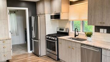 Een moderne keuken met inbouwapparatuur, houten kastjes en een visgraatvloer.