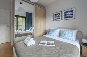 Une chambre d’hôtel avec un lit, un grand miroir, une fenêtre avec des rideaux et deux tableaux encadrés accrochés au mur.