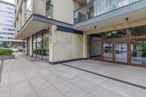 Ein modernes Gebäude mit Glastür, einem sichtbaren Schild für ein Geschäft und einem gepflasterten Bürgersteig.