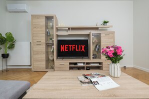 Ein Wohnzimmer mit einer Holzeinrichtungsanlage, einem Flachbildfernseher und einer Vase mit Blumen.