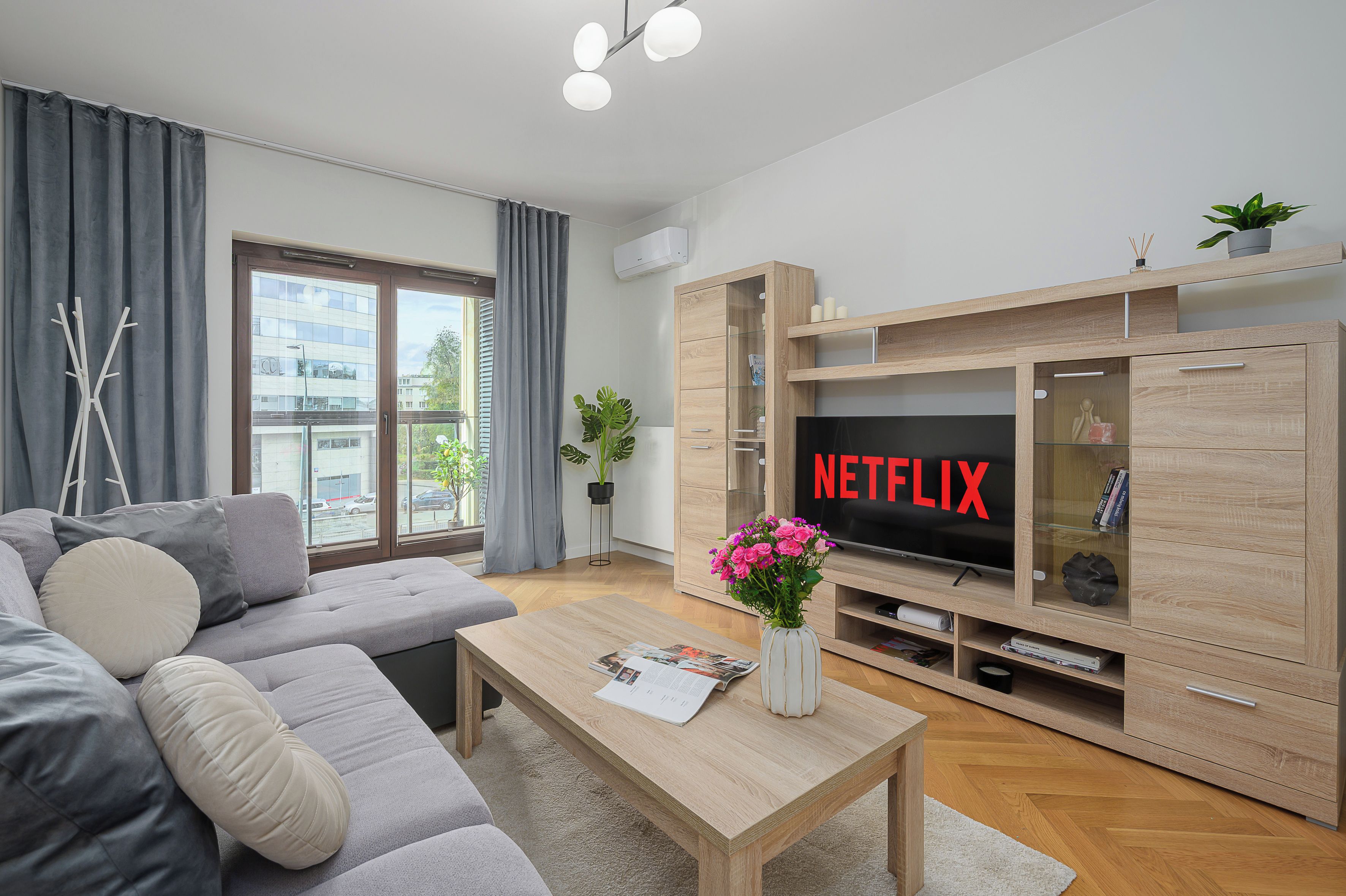 Een moderne woonkamer met een grijze bank, een salontafel, een televisie en een houten tv-meubel.