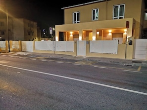 A building with a gated entrance, a street in front, and a clear road. - Vrbo Property (Olbia)