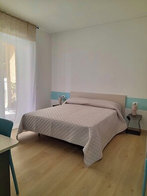 A bedroom with a bed, a bedside table, and a chair. - Vrbo Property (Olbia)