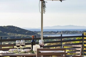 Une table à manger dressée avec des verres à vin et une bouteille, donnant sur un paysage pittoresque.