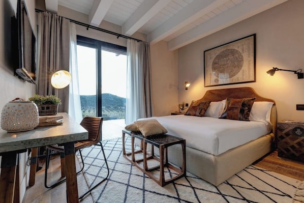 A hotel room with a bed, a desk, a chair, a table, and a view of the outdoors.