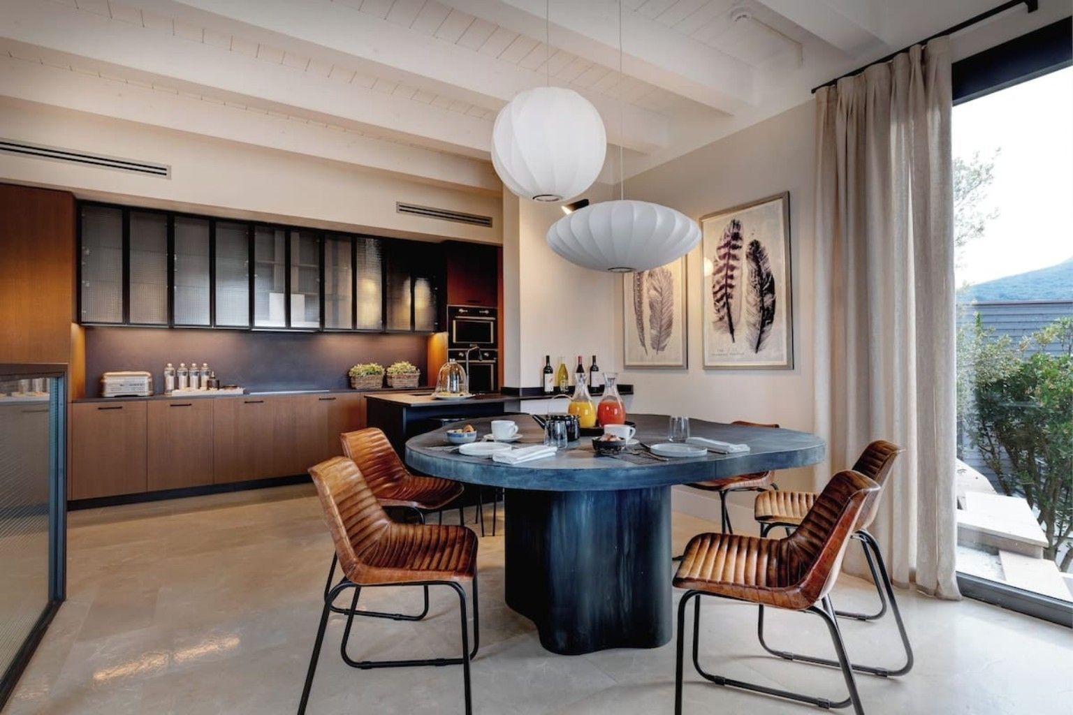 Une cuisine moderne avec une table de salle à manger ronde, deux chaises et des luminaires suspendus.