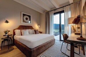 A hotel room with a large bed, a desk, a chair, a view of the outdoors, and a mounted artwork on the wall.