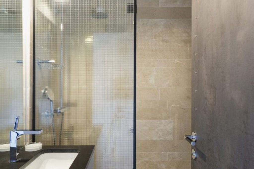 A modern bathroom with a glass shower enclosure, a sink with a faucet, and a toilet.