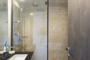 Une salle de bain moderne avec une douche à parois de verre, un lavabo avec un robinet et des toilettes.