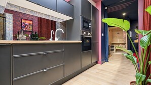 A modern kitchen with dark cabinetry, a stainless steel sink, and a large potted plant. - Vrbo Property (Armentières)