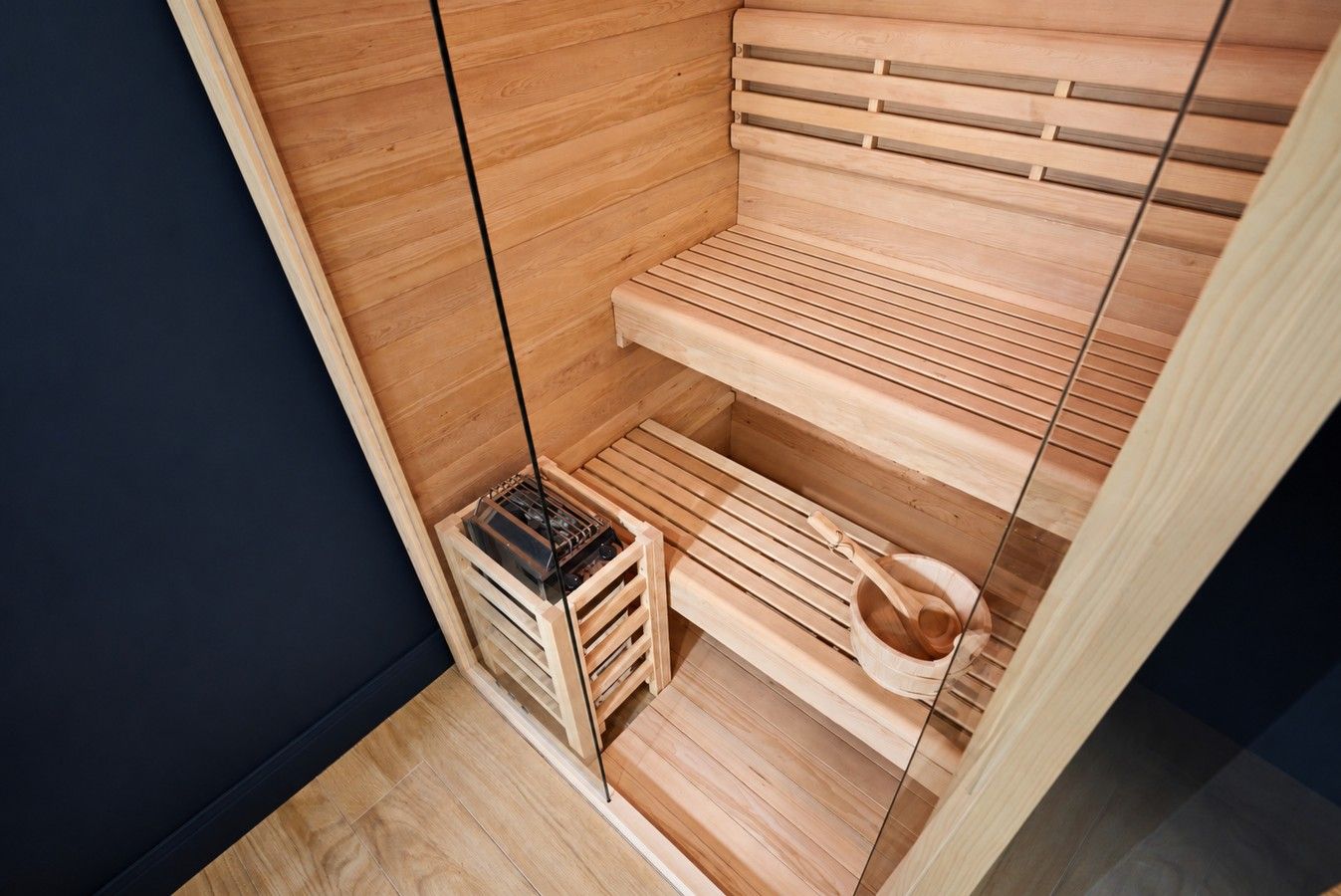 A sauna with wooden benches and a small wooden bucket.