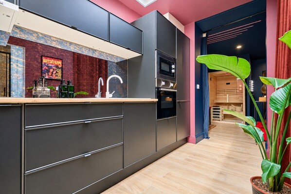 A modern kitchen with a built-in oven, a sink, and a countertop with kitchen appliances.
