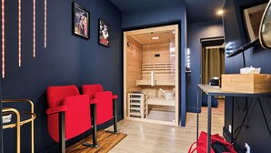 A modern room with a red sofa, wooden flooring, and a wooden sauna visible through a glass door. - Vrbo Property (Armentières)