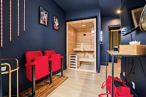 A modern room with a red sofa, wooden flooring, and a wooden sauna visible through a glass door. - Vrbo Property (Armentières)