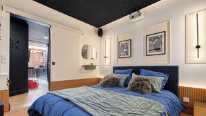 A bedroom with a bed, a nightstand, a mirror, and framed pictures on the wall. - Vrbo Property (Armentières)