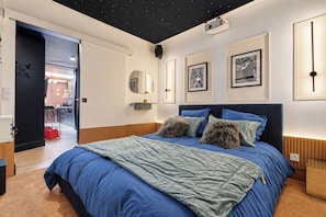 A bedroom with a bed, a nightstand, a mirror, and framed pictures on the wall. - Vrbo Property (Armentières)