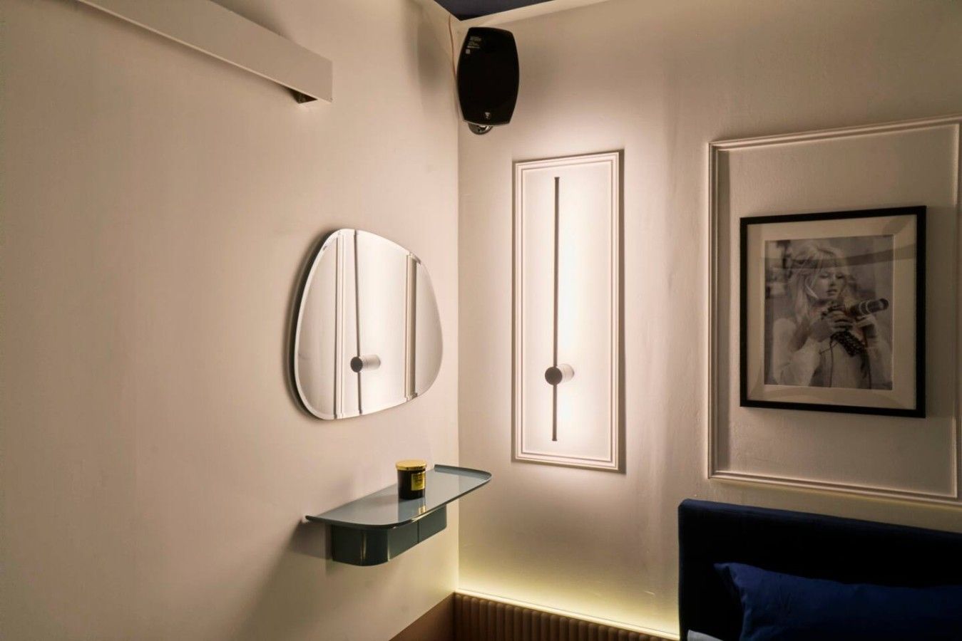 Een moderne badkamer met een glazen plank, een spiegel aan de muur en een ingelijste foto.
