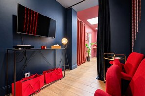A modern living room with a flat-screen TV, a floor lamp, and red furniture.