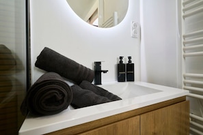 Ein Badezimmer mit einem weißen Waschbecken, einem Spiegel und zwei Shampoo-Flaschen.
