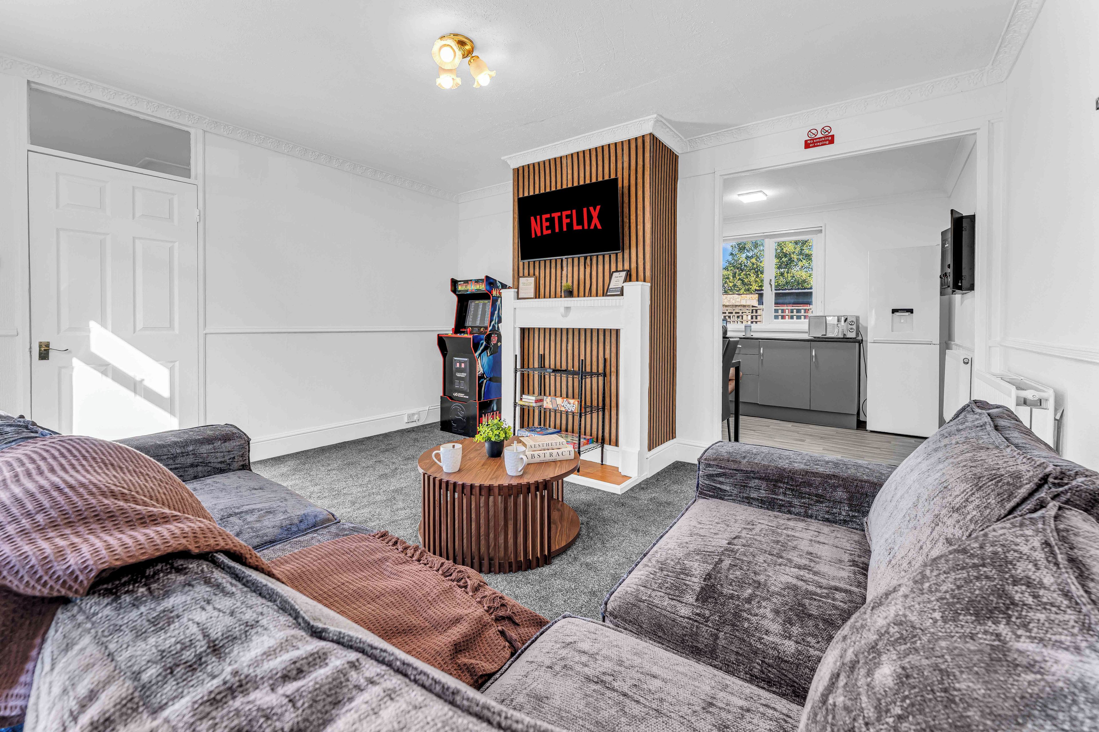 A living room with a Netflix sign, a gaming console, and a fireplace.