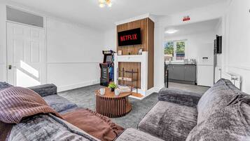 A living room with a Netflix sign, a gaming console, and a fireplace.