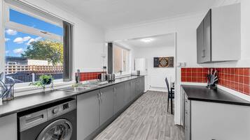 Una cocina moderna con armarios grises, lavadora integrada y ventana con vistas al exterior.