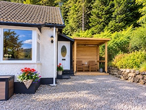 Ein Haus mit einem Ziegeldach, einer Holzveranda und einer Schotterauffahrt.