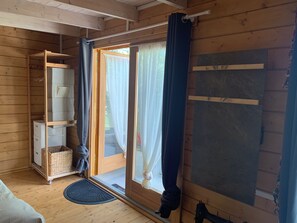 A wooden interior with a sliding glass door, a storage unit with baskets, and a mat on the floor.