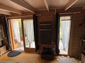 A wooden cabin with a sliding glass door, a small table, and a bench.