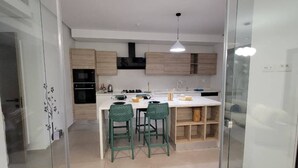 Een moderne keuken met een centraal eiland, twee barkrukken en een hangende pendantlamp.