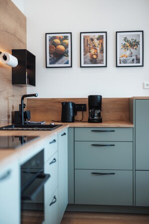 A modern kitchen with a wooden countertop, a coffee maker, and a built-in oven. - HunsrückQuartier Vacation Home - Vacation Home with Hot Tub and Sauna (Mastershausen)