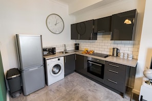 Eine kompakte Küche mit Kühlschrank, Waschmaschine, Mikrowelle, Spüle und Herd.