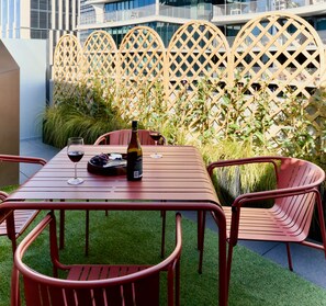 A patio with a table set for two, featuring a bottle of wine, a glass, and a plate of grapes. - The Wood - In the heart of Collingwood. (Collingwood)