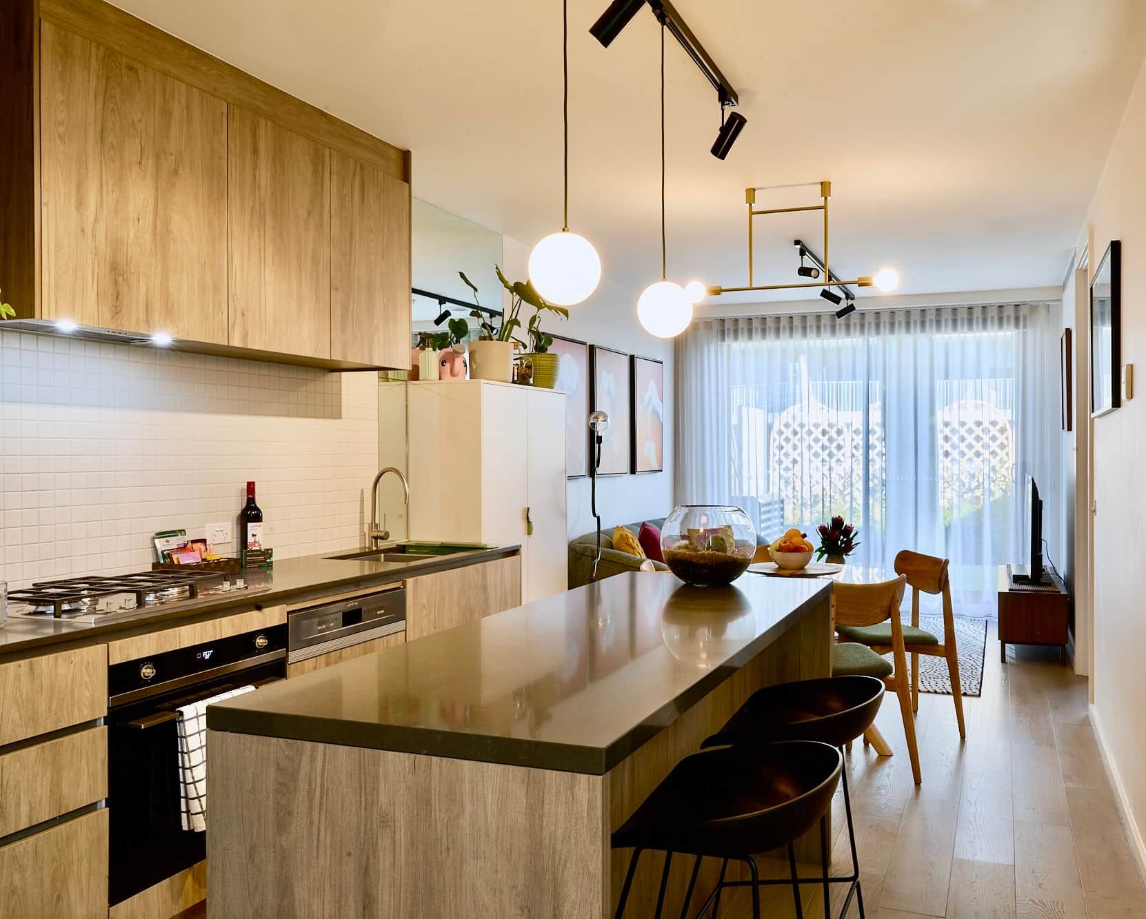 A modern kitchen with a central island, built-in appliances, and pendant lighting.