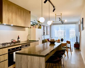 A modern kitchen with a central island, built-in appliances, and pendant lighting. - The Wood - In the heart of Collingwood. (Collingwood)