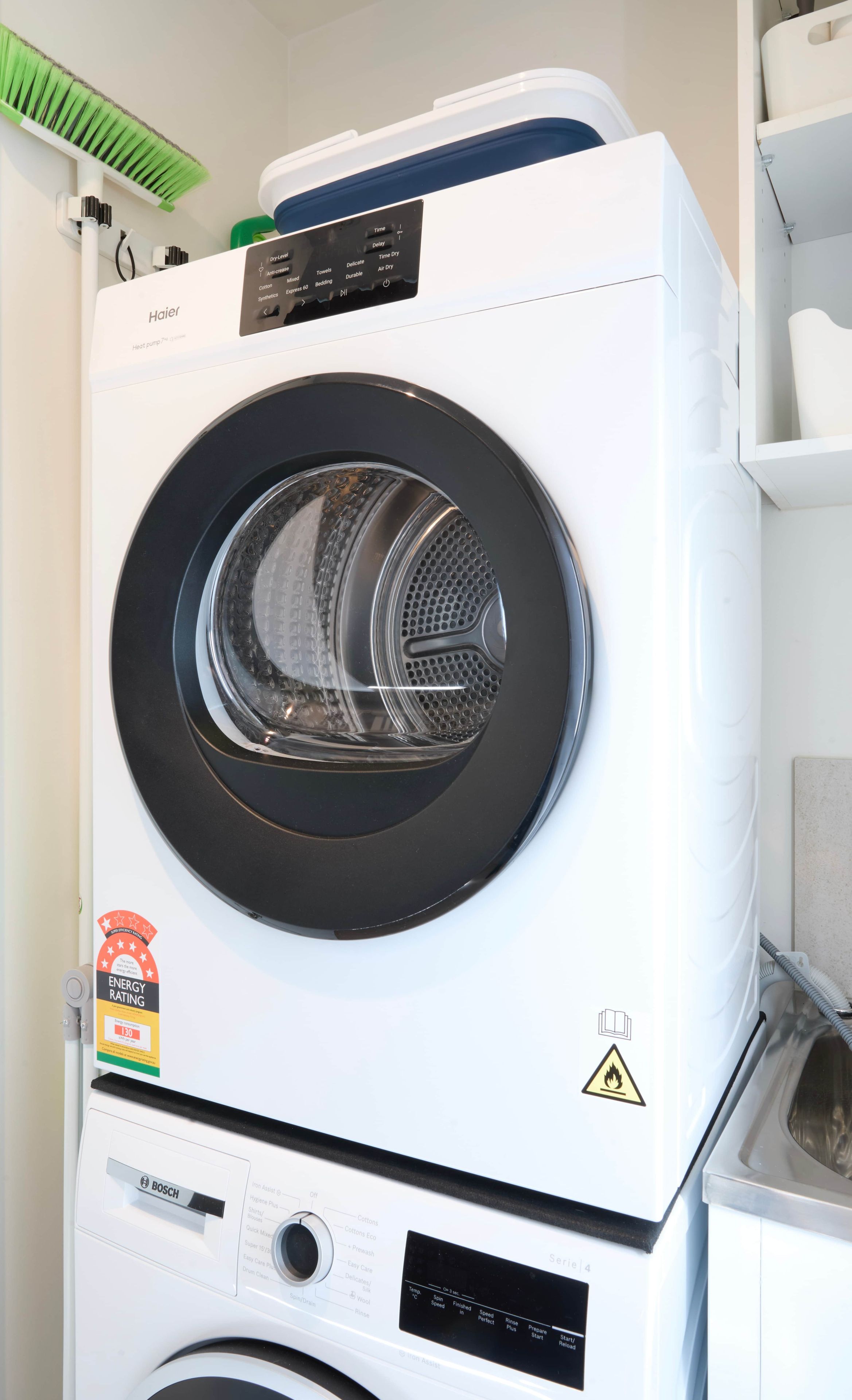 A front-loading Bosch washing machine with a digital display, energy rating label, and a warning label.