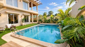 Un área moderna junto a la piscina con una piscina azul cristalina, una silla de descanso y una mesa de comedor.