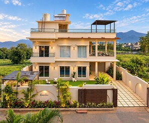 Una casa moderna de varios pisos con un balcón, ventanas amplias y un jardín bien cuidado.