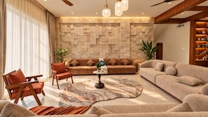A modern living room with a stone accent wall, a round coffee table, and a variety of seating options.
