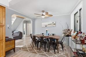 A dining area with a wooden table and chairs, a ceiling fan, and a view of the outdoors through a window. - Spacious 6BR Retreat Steps from Beach & Boardwalk (Wildwood Crest)